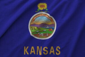 Kansas US state flag depicted on folded wavy fabric of old cloth close up